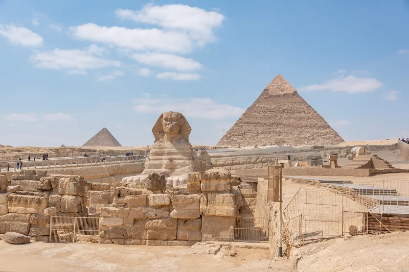 a group of stone statues in front of a pyramid of Giza