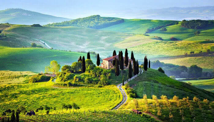 Rolling hills of Tuscany showcase a picturesque landscape, characterized by lush greenery and gentle slopes while your italian tour